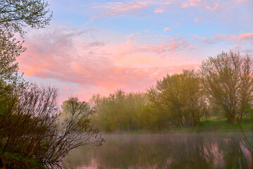 Fog over the river during early spring dawn with red clouds.