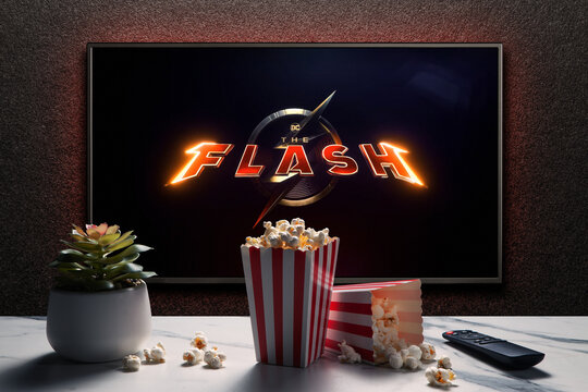 TV screen playing The Flash trailer or movie. TV with remote control, popcorn boxes and home plant. Astana, Kazakhstan - May 15, 2023.