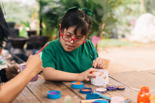 Little girl painting flower pots in the garden.