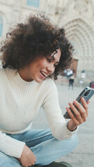 Close up, young woman scrolls on a cell phone. Happy girl uses mobile phone on old city background