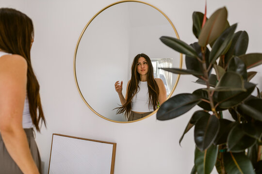Woman reflected in circular mirror at home
