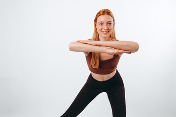 Half-length portrait of a young red-haired girl doing sport exercises and warming up isolated on white background.