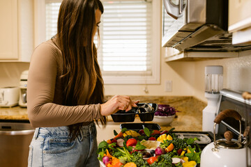Woman prepares healthy vegan lunch box in kitchen
