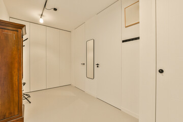 an empty room with white walls and wood doors on either side, there is a door in the wall that leads to another room