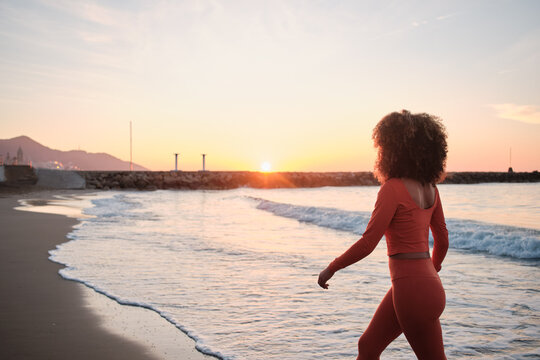 Anonymous sportswoman walking on the beach