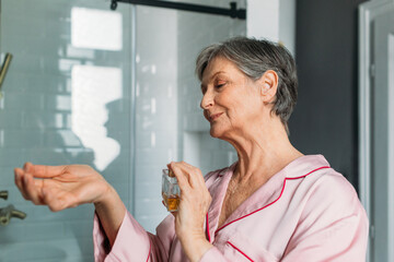 Senior Woman Spraying Perfume on Her Skin