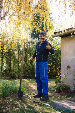 Gardener with a spade stand and talk in the garden.