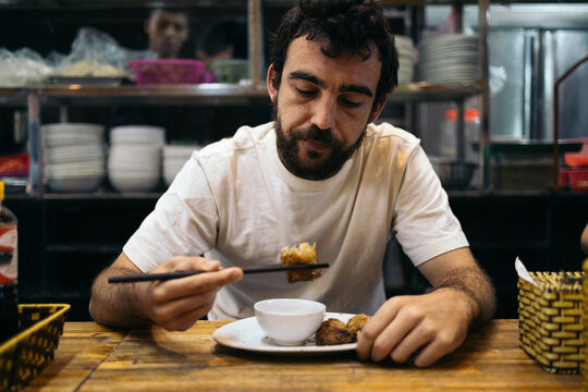 Caucasian man eating oriental food in Southeast Asia