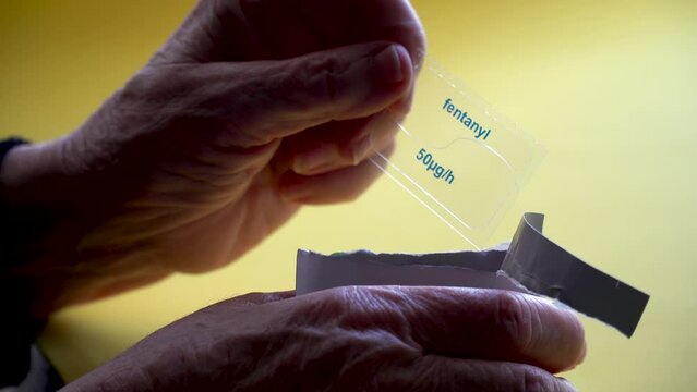 An elderly person takes out a fentanyl medical patch.