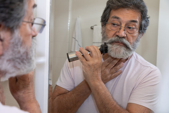Retired latin man shaving in his bathroom