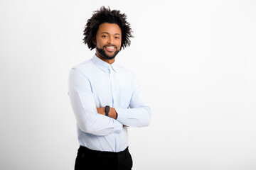 Handsome curly man looking at camera standing with arms crossed isolated on white background. African-American male employyee with curly hair in formal white shirt with folded hands