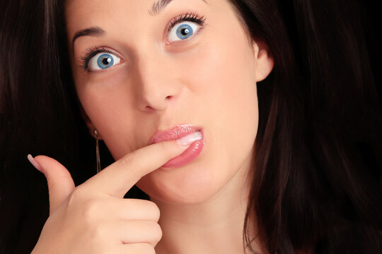 Portrait of a beautiful caucasian young woman with beautiful blue eyes and finger in her mouth