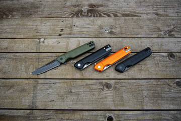 Folding penknives in different colors. Pocket knives for everyday carry. Various knives for hunting, sports and recreation. Wooden back.