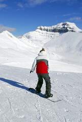 Fototapeta na wymiar Girl snowboarding on the backdrop of scenic view in Canadian Rocky mountains ski resort