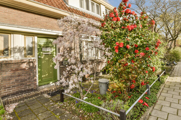 a house with red flowers in the front and green shutters on the side, taken from an angleer's perspective