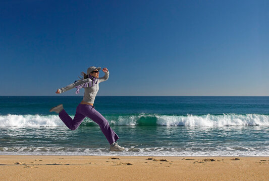 Young woman jumping for fun in a beautiful beach
