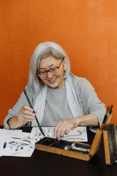 Smiling senior woman creating calligraphy works