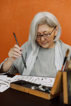 Elderly woman practicing calligraphy in workshop