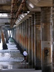 Woman running on shore under pillared walkway