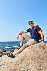 Fototapeta na wymiar Middle aged hiker sitting on a rock