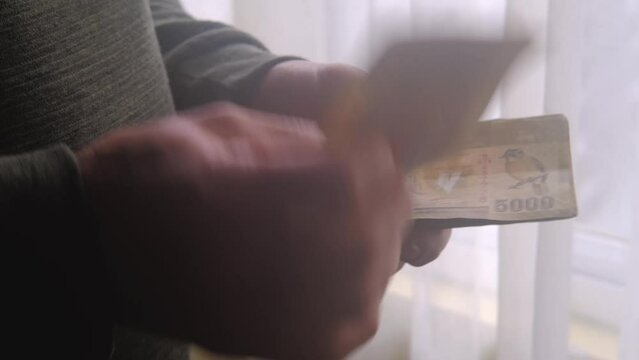 man holding, counts lot of national currency of Sri Lanka, paper money bills Rupee banknotes, devaluation, high inflation of state, exchange rate on travel, vacation, savings, banking, tax payment