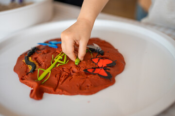 A little girl playing with plasticine and toys insects. Sensory development and experiences, themed activities with children, fine motor skills development