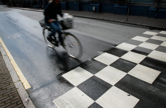 Wet morning traffic with speedy cyclist passing crosswalk. Motion blur.