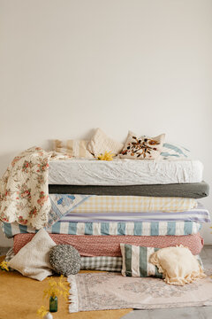 a pile of mattresses with pastel colored sheets
