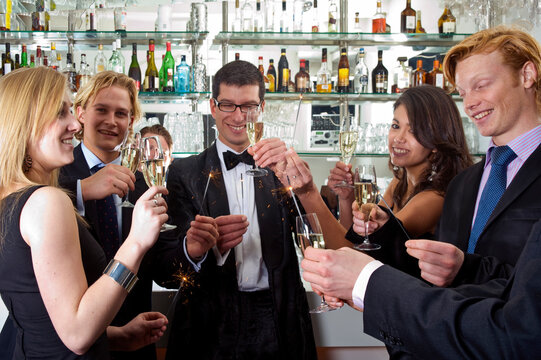 several people toasting with champagne on new years eve while holding sparkling sticks