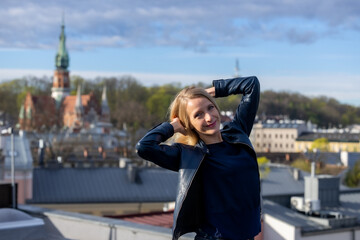 Beautiful woman in a blue jacket, dark shirt and blue jeans posing against the background of the city of Krakow