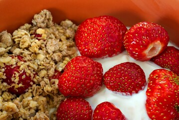 Cereals with strawberry and yogurt in orange bowl