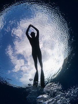 sihouette of female free diver underwater with sky