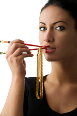 portrait of a cute woman playing with a glod necklace and red chopstick