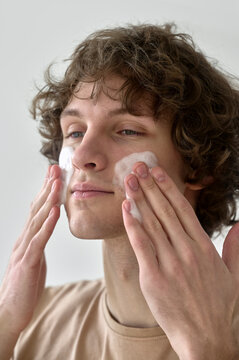 A man applies facia foam while taking care of his skin