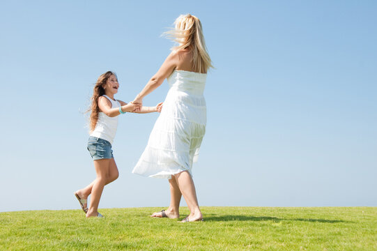 Young girl playing on meadow with her mum