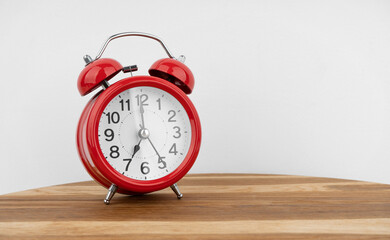 Red alarm clock on grey wall background