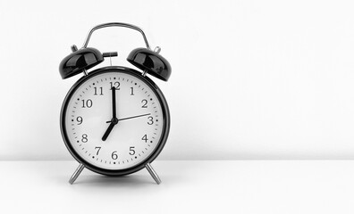 Black alarm clock on white wall background