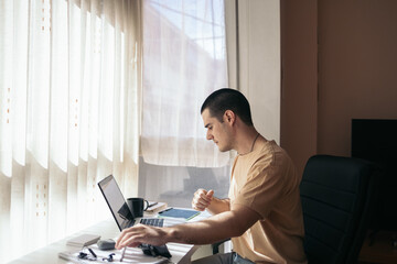 Home office: young man teleworking with laptop at home