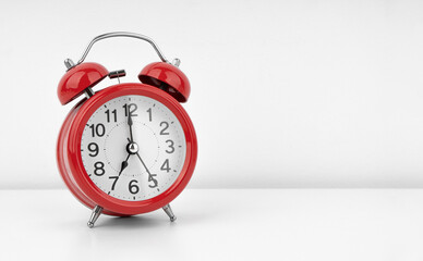 Red alarm clock on white wall background