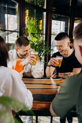 Happy group of friends drinking and clinking with beer and cocktails at brewery bar restaurant. Beverage life style concept with guys and girls having fun together
