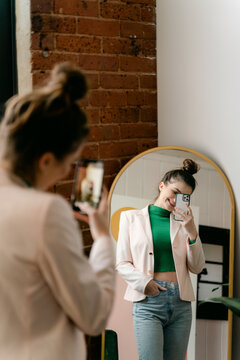 young confident woman taking a selfie in mirror