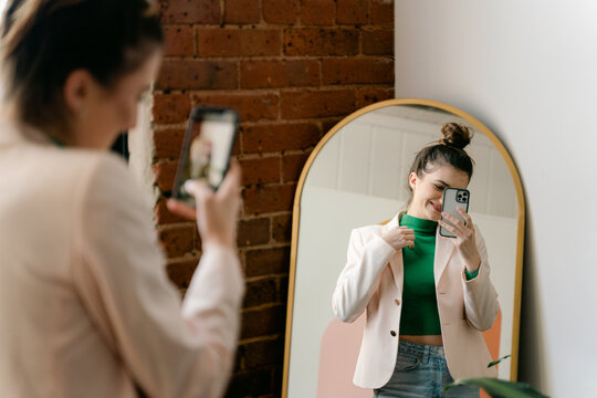 young confident woman taking selfie of reflection in her home