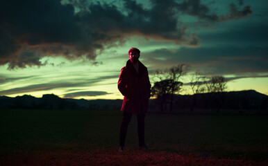 Surreal man silhouette standing at dramatic sunset field