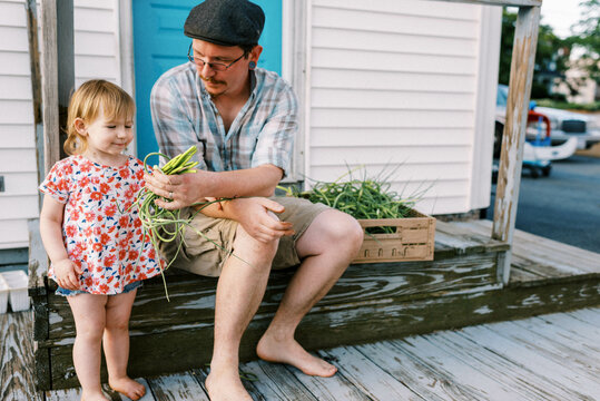 father sitting on porch with his daughter, doing farm chores together