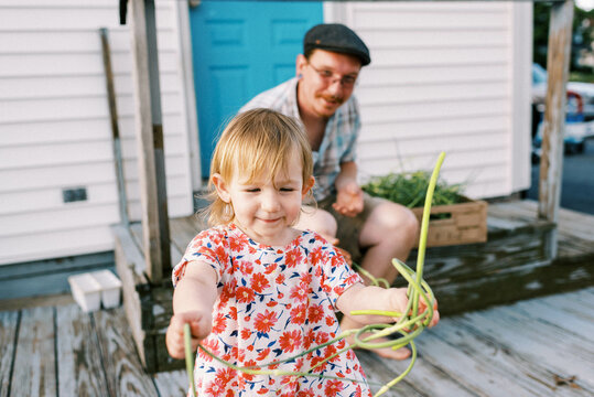 father sitting on porch with his daughter, doing farm chores together
