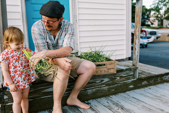 father sitting on porch with his daughter, doing farm chores together