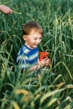 Smiling happy toddler in field of garlic in urban garden