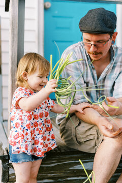 father sitting on porch with his daughter, doing farm chores together