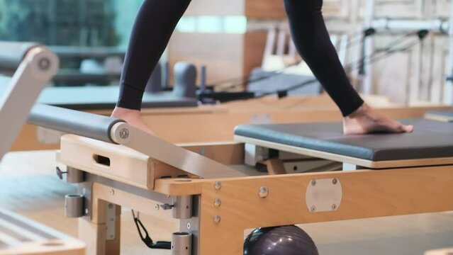 Effective pilates workout in gym professional coach doing stretching exercise for legs on modern reformer sportive woman enjoying training for flexible body