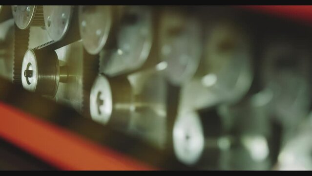 The glass enters the machine on rollers and undergoes a hardening process. The main gears that drive the machine rotate in the frame.